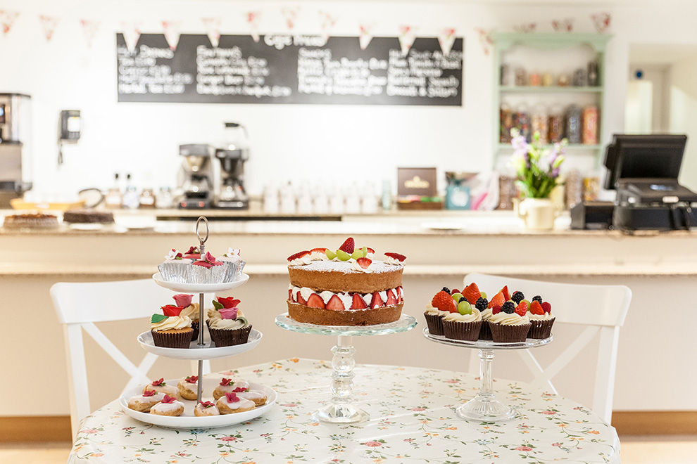 Victoria Sponge cake and fruit-topped cupcakes on display in the Museum's Cafe.